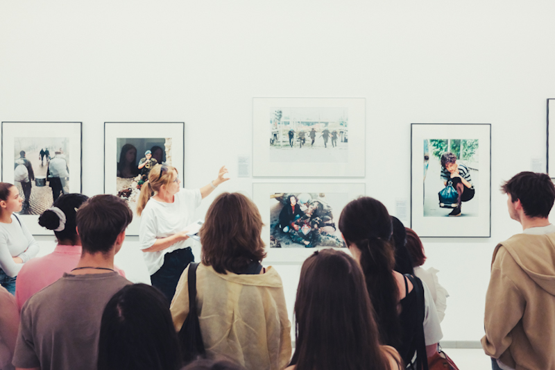 Lernende betrachten gerahmte Pressefotografien während einer Führung in der Ausstellung