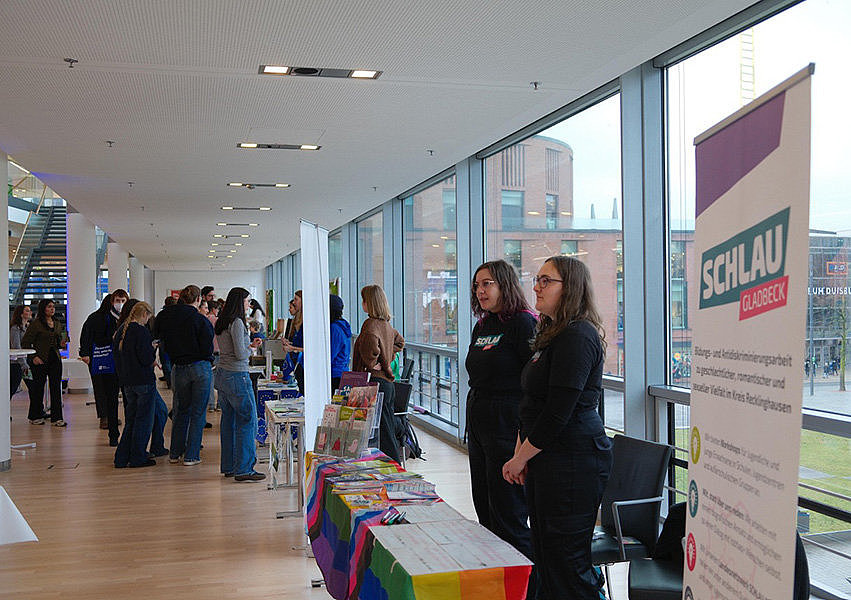 Messestand mit zwei Schülerinnen und Besuchern im Hintergrund im 