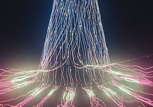 Lichtinstallation im Gasometer mit farbigen Lichtlinien und Besuchergruppe am Boden