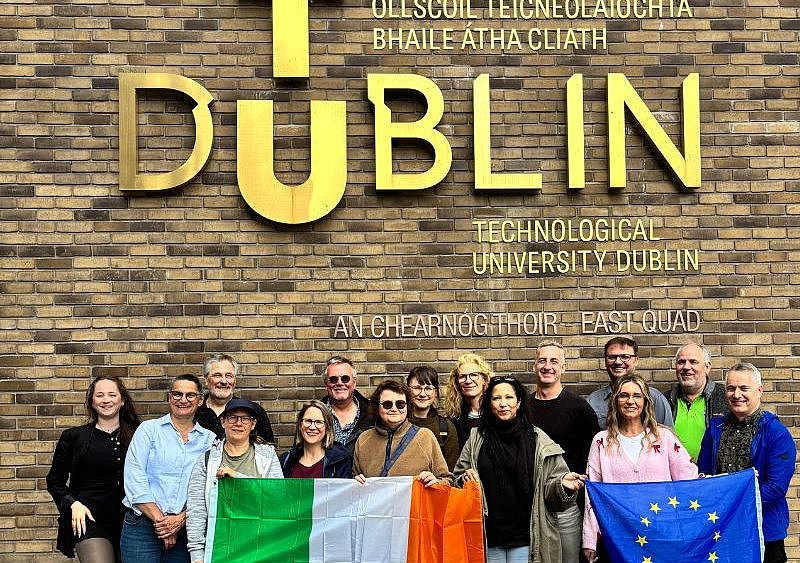 Die Gruppe des Jobshadowings steht vor einer Wand, auf der TU Dublin steht und posiert zum Gruppenfoto mit EU-Flagge