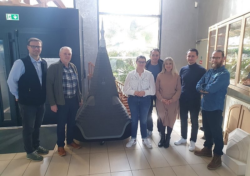 7 Personen in der Vorhalle der Compagnos in La Rochelle um ein ein Dachmodell stehend.