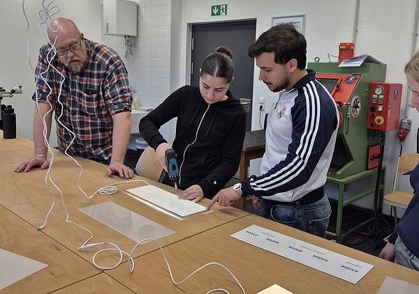 Praktische Umsetzung am Arbeitstisch durch eine Schülerin und einen Schüler unter Aufsicht von Herrn Stanies