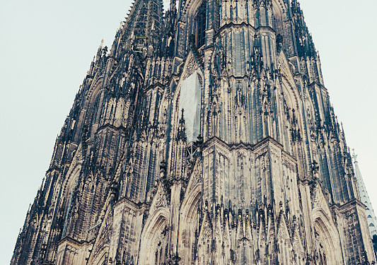 Außenansicht des Kölner Dom mit seinen hohen gotischen Türmen und reich verzierten Fassaden, aufgenommen aus einer niedrigen Perspektive.